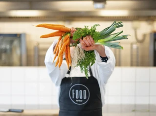Person holding carrots in a kitchen