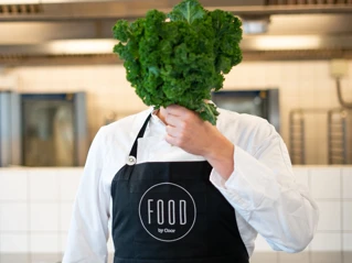 Person med grönkål framför ansiktet